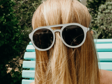 A person with their long hair over their face wearing sunglasses