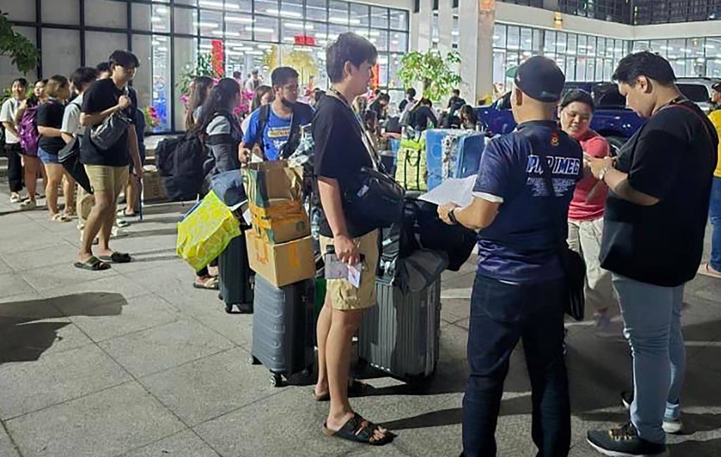 A police officer (front, centre) talking to foreign nationals after a raid in a scam centre within a complex of buildings in Bamban town of Tarlac province in March last year. Photo: PAOCC/AFP